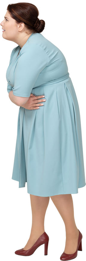Vista laterale di una donna in abito blu che soffre di mal di stomaco