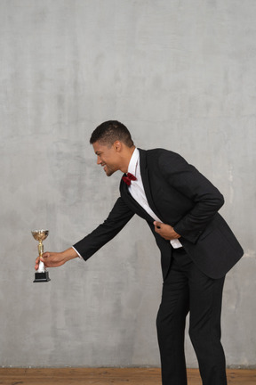 Man in suit presenting an award to someone small