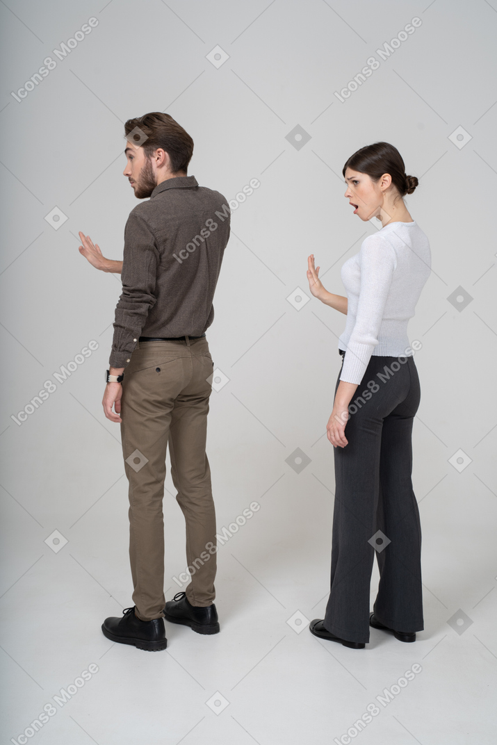 Three-quarter back view of a young couple in office clothing outstretching hand