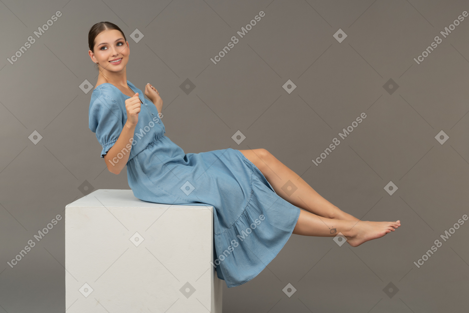 年轻女子坐在立方体上试图保持平衡的侧视图