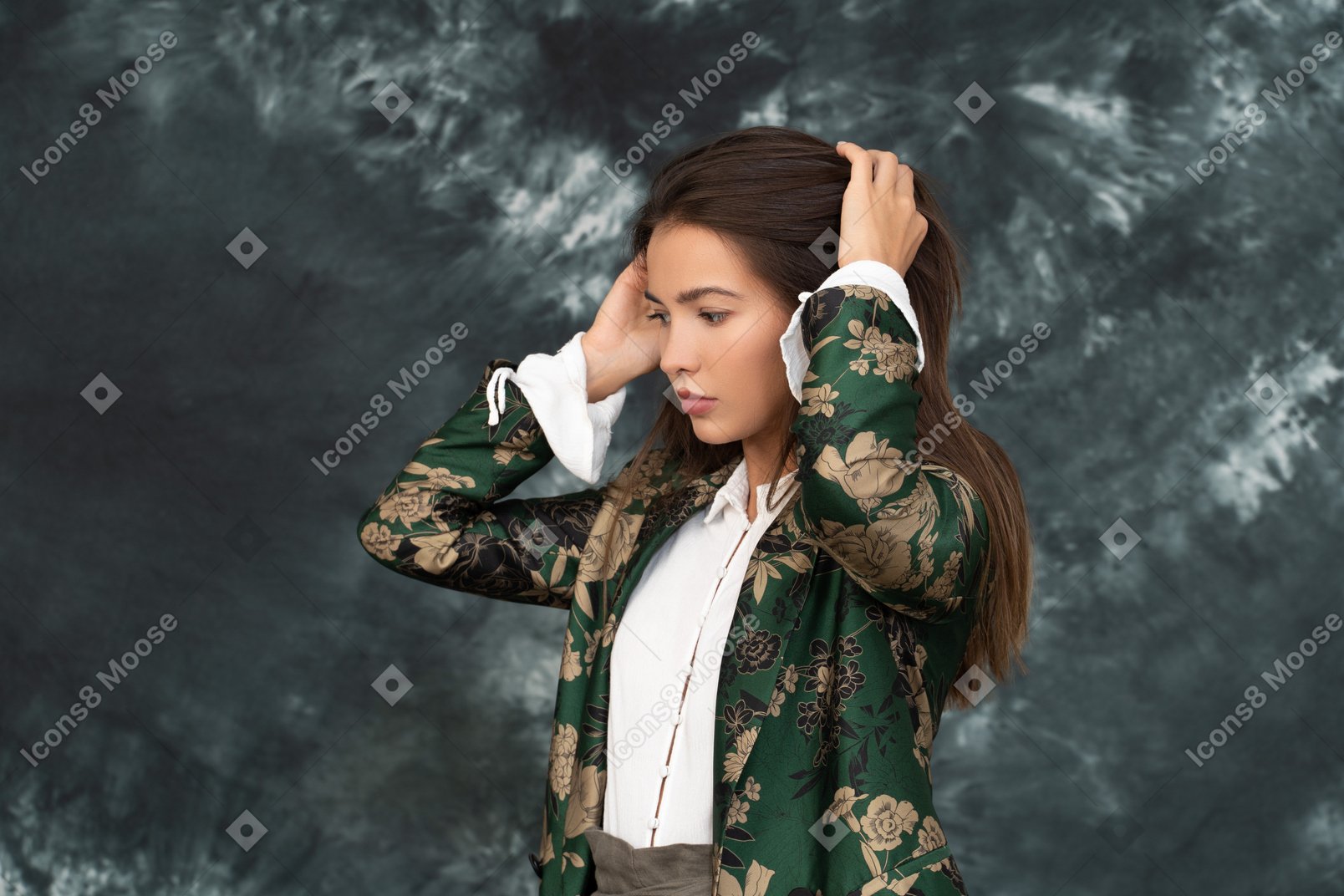 Задумчивая деловая женщина в зеленой шелковой куртке трогает волосы