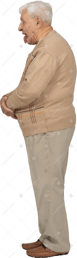 Vista laterale di un uomo anziano in abiti casual che mostra la lingua