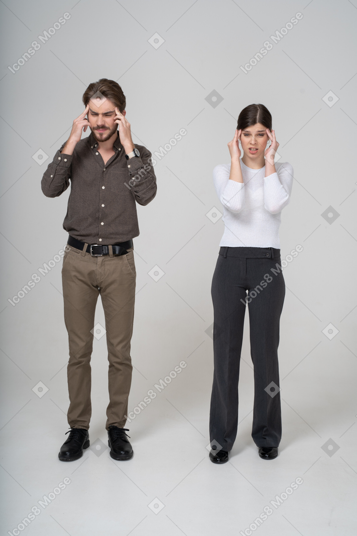 Vista frontal de una pareja joven conmocionada en ropa de oficina tocando la cabeza
