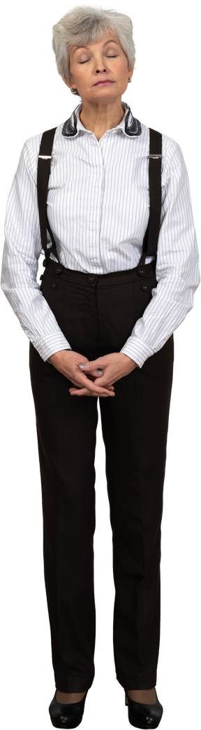 Front view of an old displeased female in office clothes grimacing and holding hands together