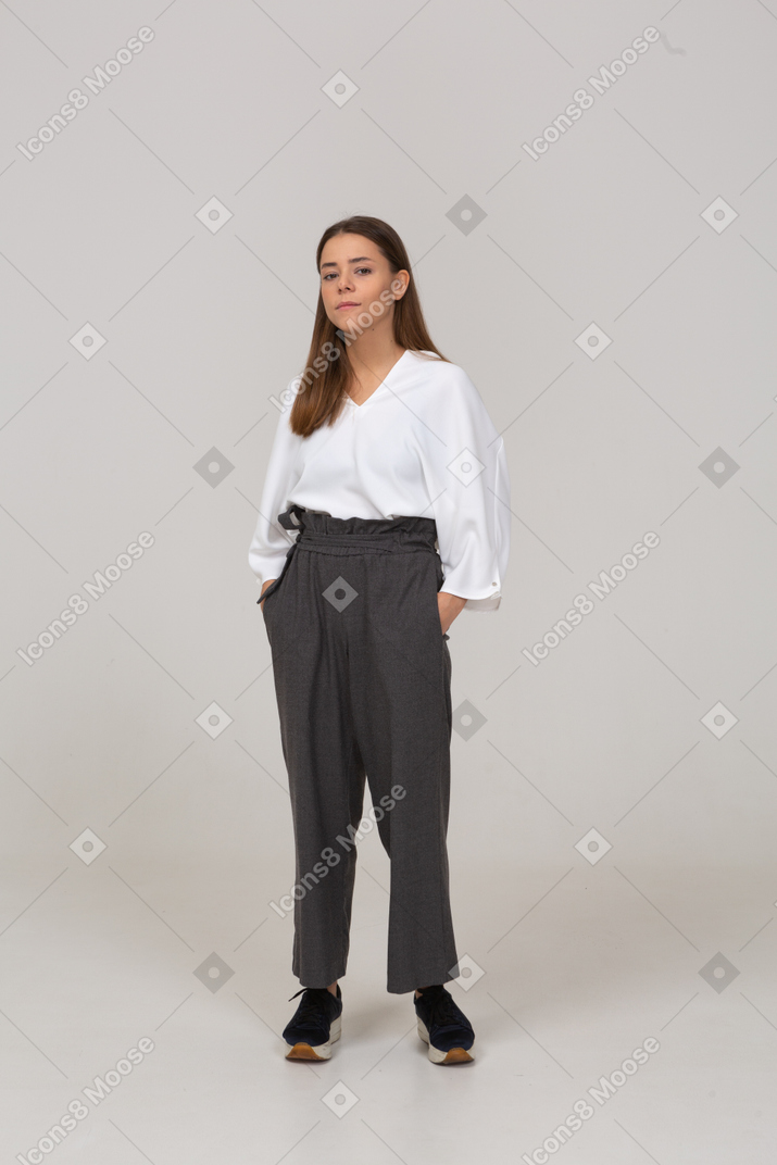 Vue de face d'une jeune femme en vêtements de bureau mettant les mains dans les poches
