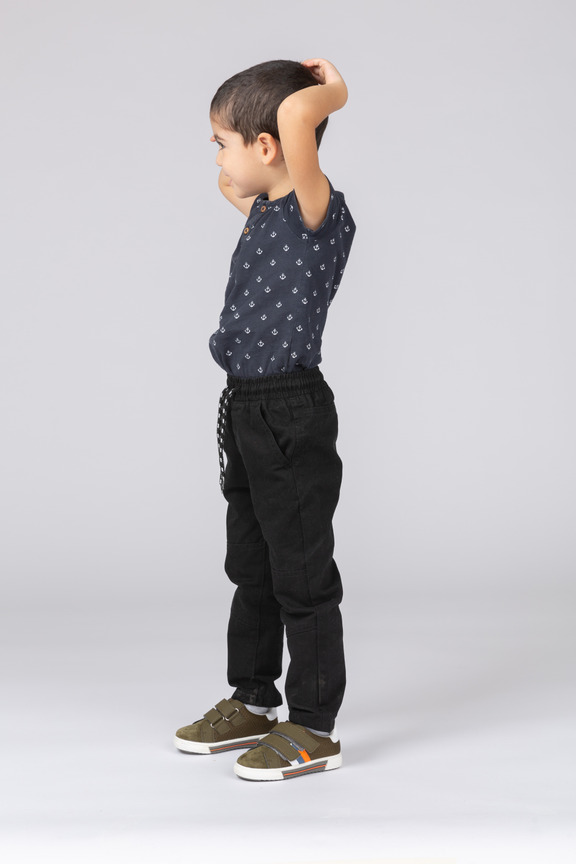 頭の上に手でポーズをとってかわいい男の子の正面図 のフォト