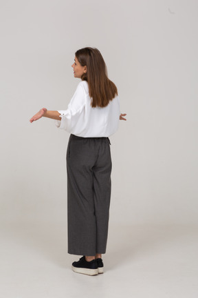 Vista de três quartos das costas de uma jovem com roupas de escritório estendendo os braços