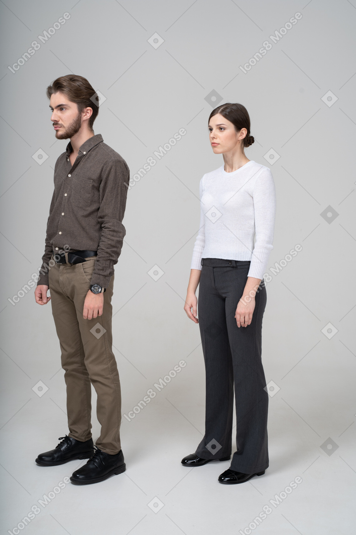 Three-quarter view of a young couple in office clothing standing still
