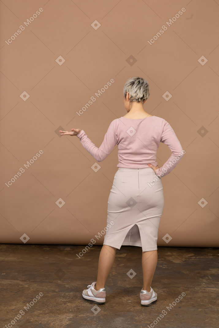 Retrovisor de uma mulher com roupas casuais em pé com a mão estendida