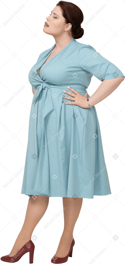 Side view of a woman in blue dress posing with hands on hips