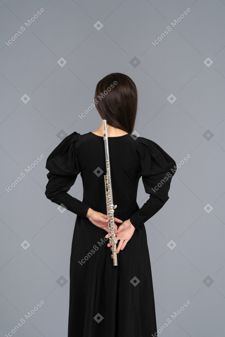 Back view of a young lady in black dress holding flute behind
