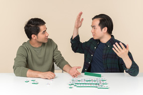 Interracial friends sitting at the table and playing scramble