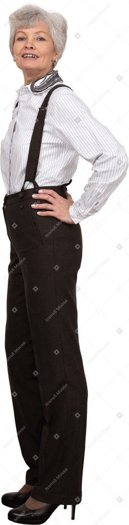 Вид сбоку гордой старушки, положившей руки на бедра в офисной одежде