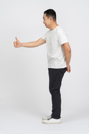 Side view of a man in casual clothes showing thumb up