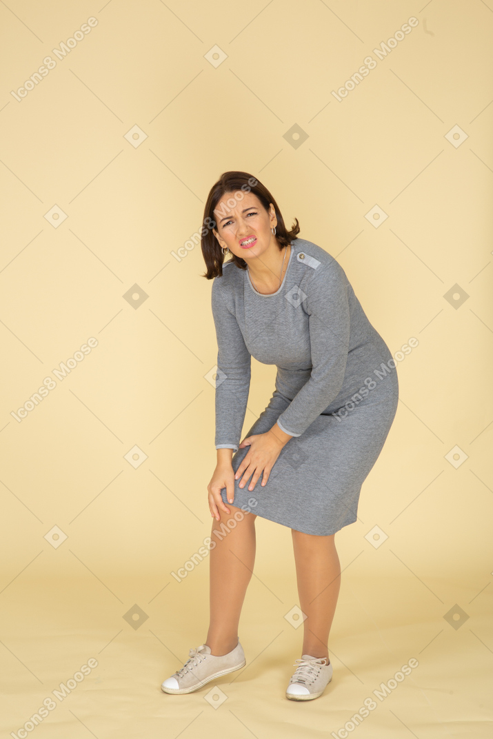 Vista lateral, de, un, mujer, en, vestido gris, tocar la rodilla