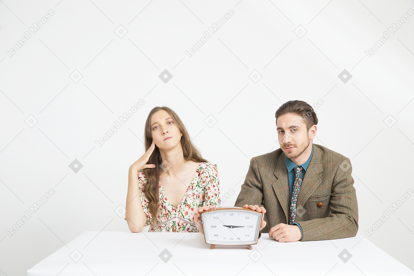 Casal sentado à mesa e segurando um relógio