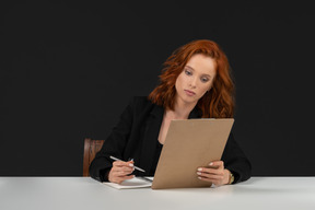 A frontal view of the beautiful woman sitting at the table with papers