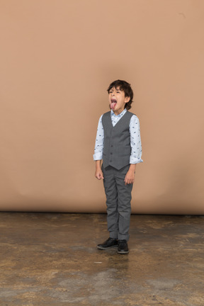 一个穿西装的男孩的正面图，露出舌头