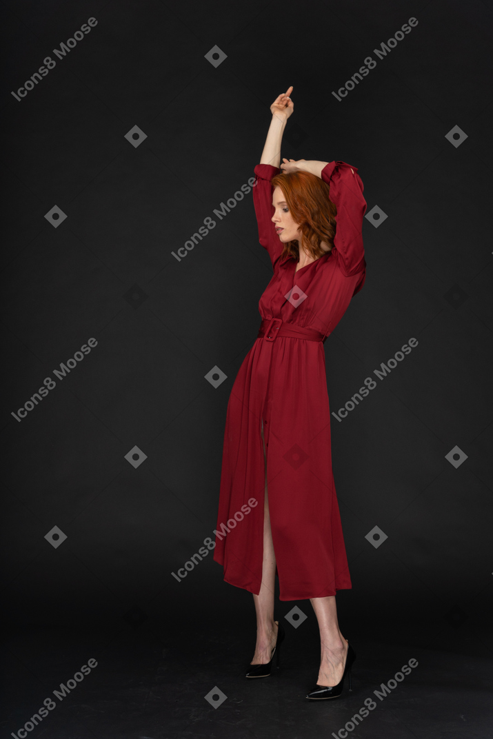 포즈를 취하는 빨간 드레스를 입은 젊은 생강 아가씨