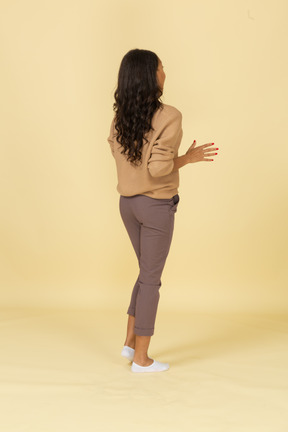Three-quarter back view of a dark-skinned young female outspreading her fingers