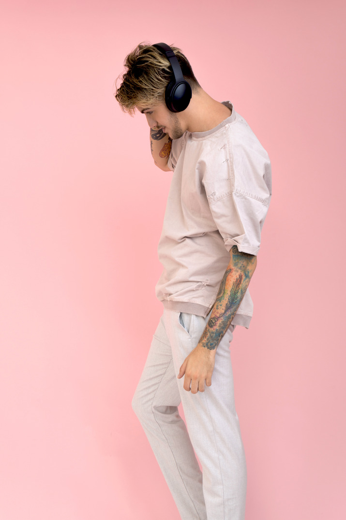 Attractive young guy standing in profile and wearing headphones