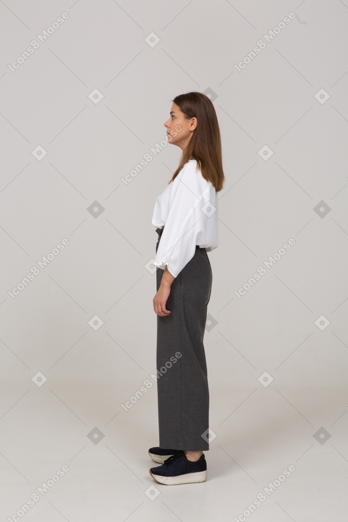 Vista laterale di una giovane donna sorpresa in abiti da ufficio che guarda da parte