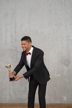 Man in suit presenting an award to someone small