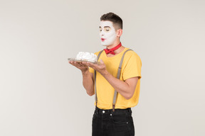 Male clown holding a white cake