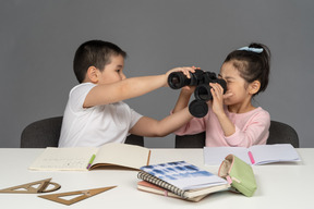 Boy taking binoculars from his sister