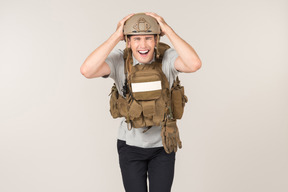 Laughing male journalist in bulletproof vest touching his head