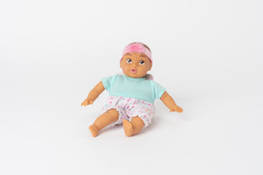 Cute baby doll seduto isolato su uno sfondo bianco semplice