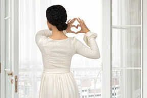 Donna vicino alla finestra che mostra il cuore con le sue mani