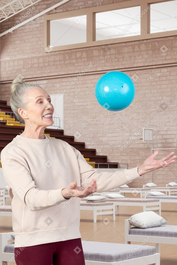 A woman is playing with a ball in a room with beds