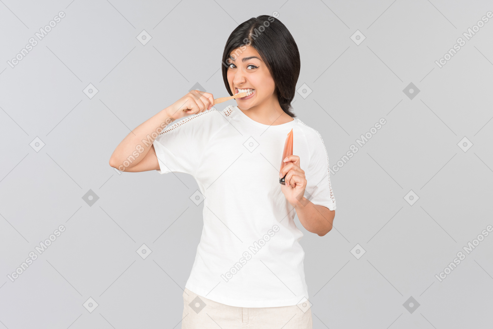 Young indian woman brushing her teeth and holding toothpaste