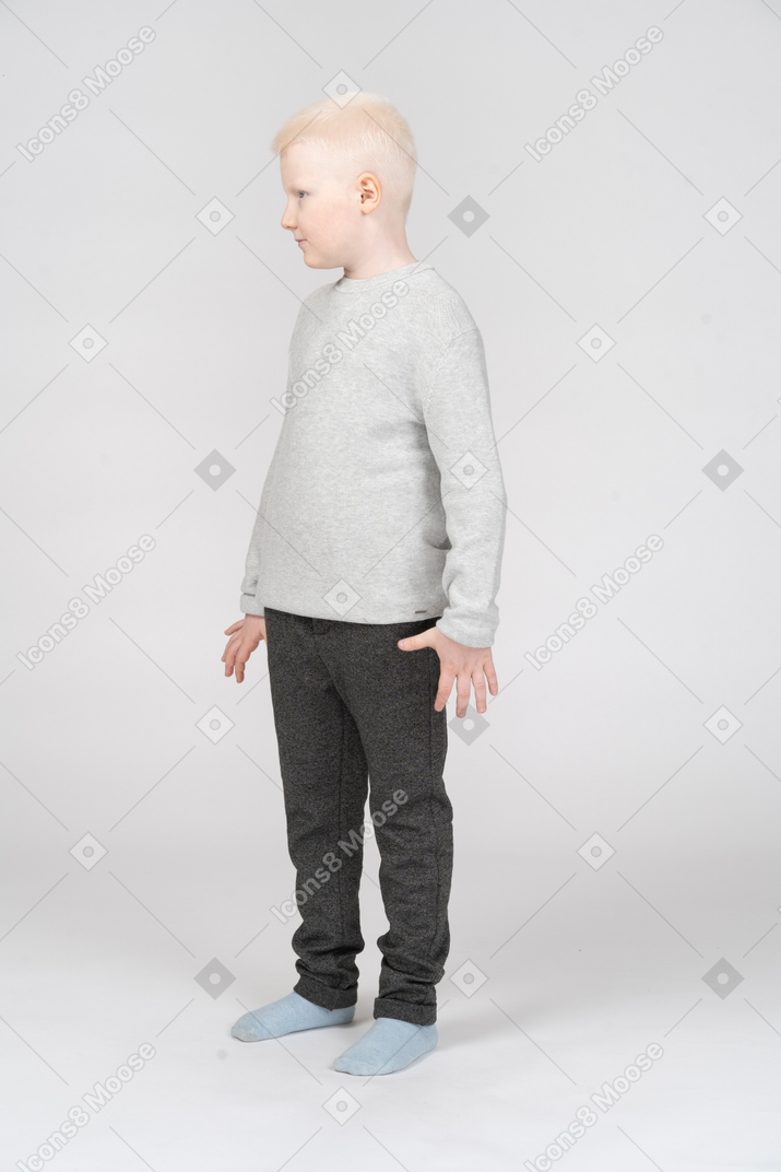 Вид в три четверти на маленького мальчика, стоящего с растопыренными пальцами