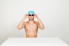 Bare chested swimmer adjusting goggles
