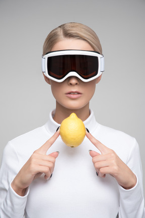 Mulher loira com óculos de esqui segurando limão