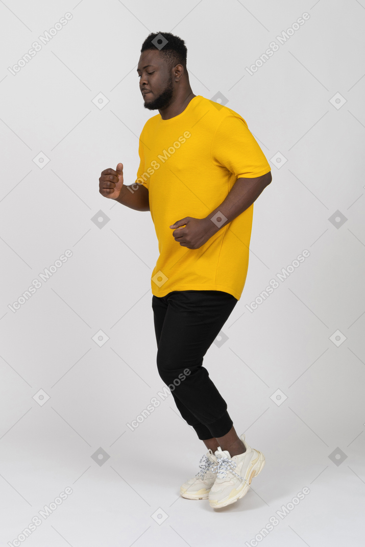 Dreiviertelansicht eines laufenden jungen dunkelhäutigen mannes in gelbem t-shirt