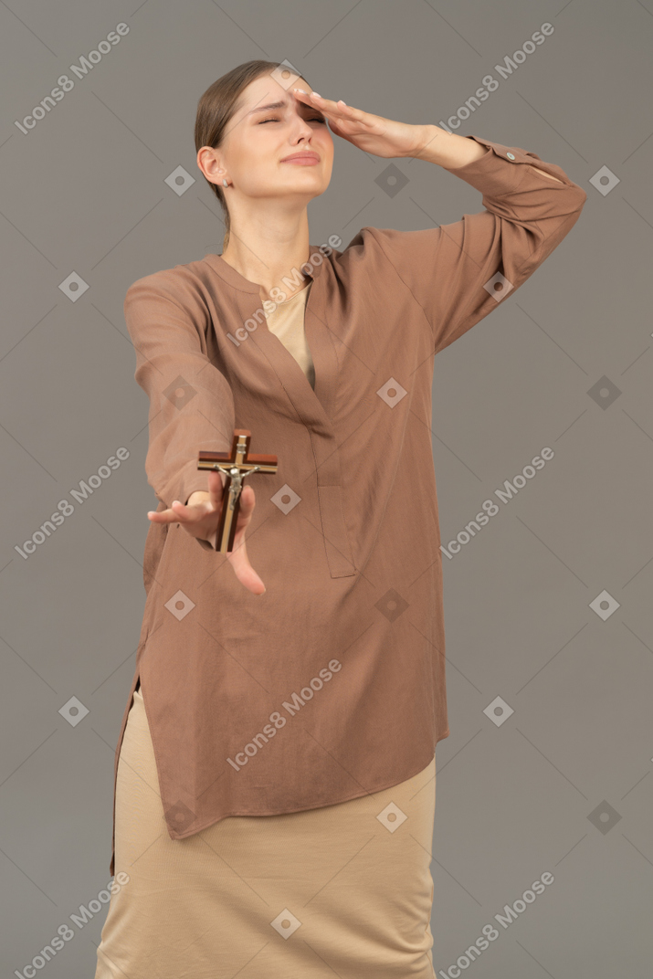 Young christian woman holding a cross and crying