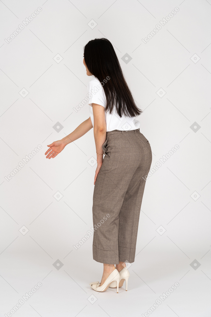Side view of a young lady in breeches and t-shirt outstretching her hand and bending down