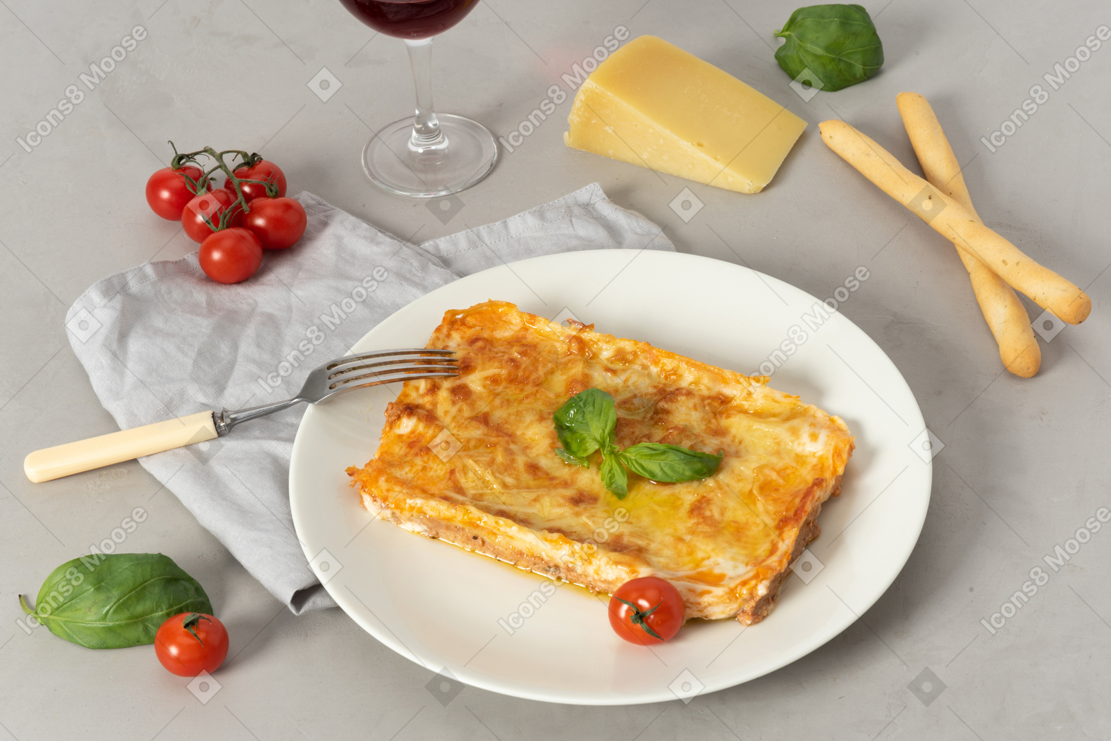 Lasagna on the plate, cherry tomatoes, piece of cheese and grissini