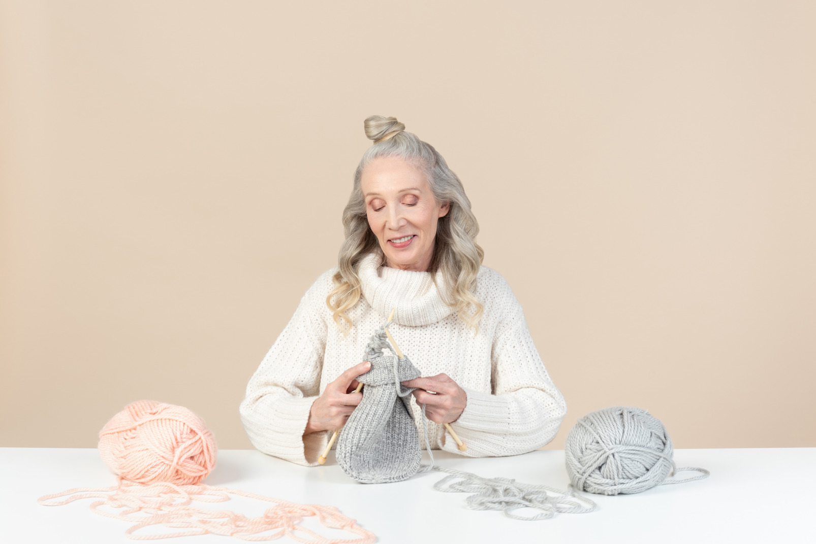 Old woman sitting at the table ad knitting