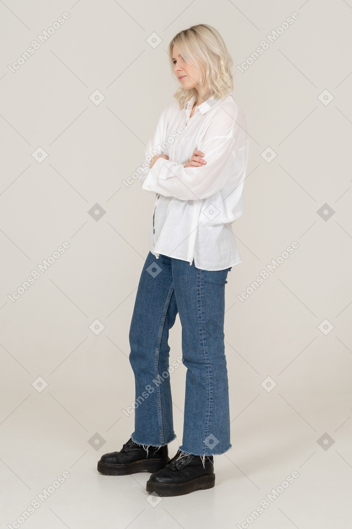 Dreiviertelansicht eines weiblichen blonden modells in der freizeitkleidung, die hände kreuzt