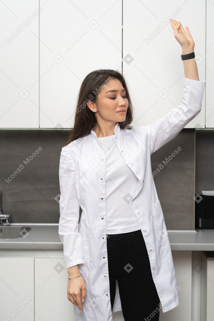 A woman in a lab coat raising her hand