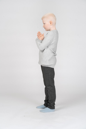 Side view of a little boy with hands crossed