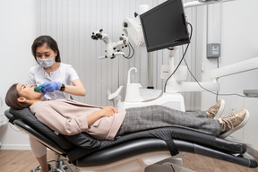 Toute la longueur d'une femme dentiste faisant un dossier dentaire à sa patiente dans une armoire d'hôpital