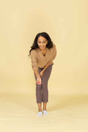 Front view of a dark-skinned young female bending down and outstretching hand