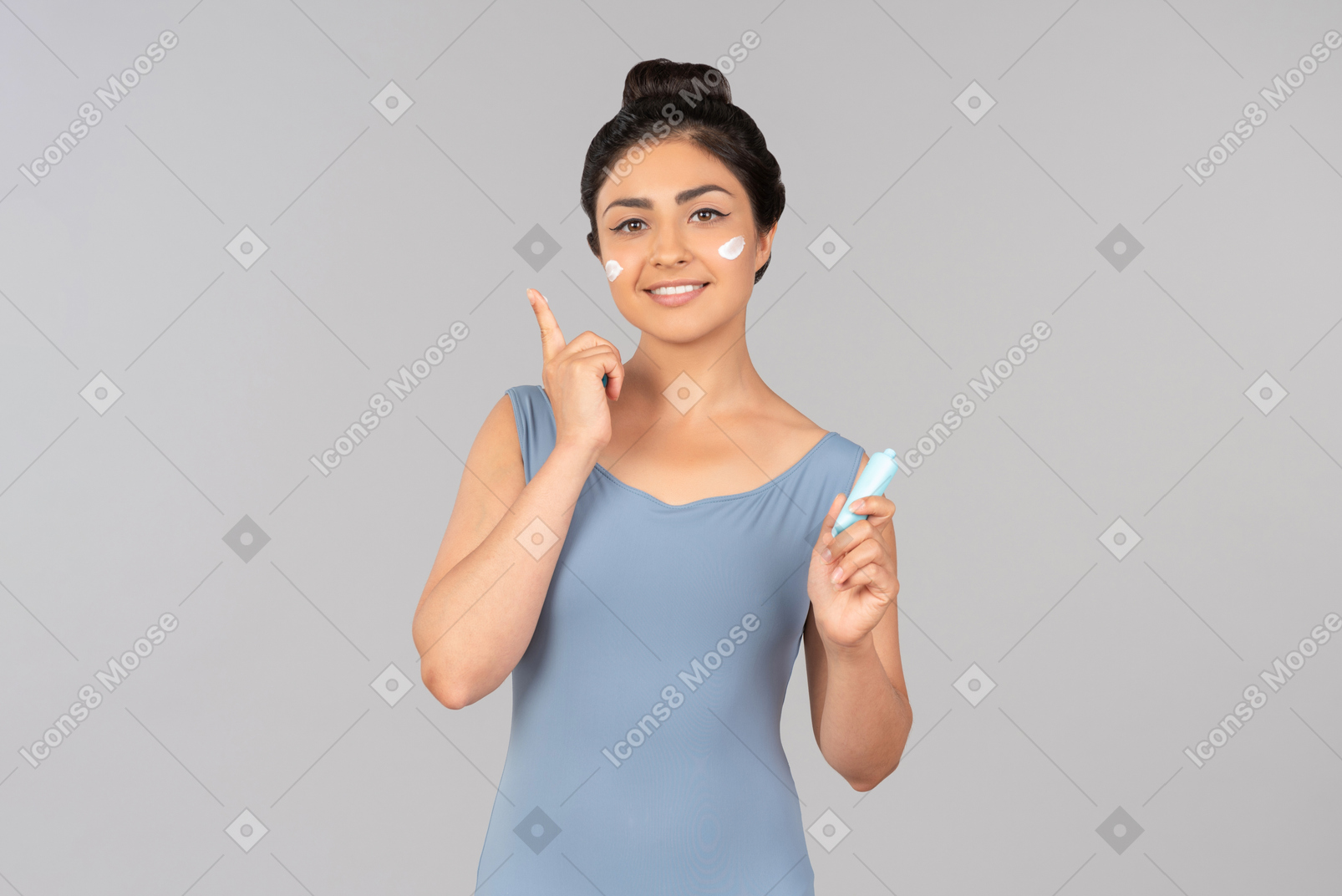 Молодая индийская женщина в синей майке, применяя крем для лица