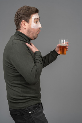 Vista lateral de un fanático del fútbol masculino sorprendido sosteniendo una cerveza