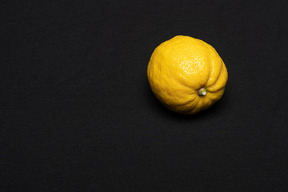 Lonely lemon lying on black background